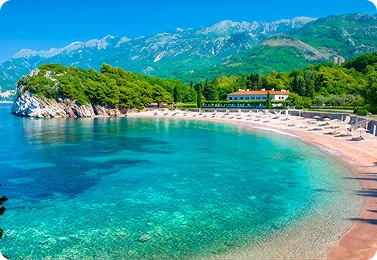 Beach curving between mountains and clear blue water