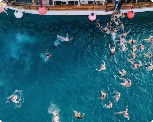 Guests swimming in clear water beside the boat